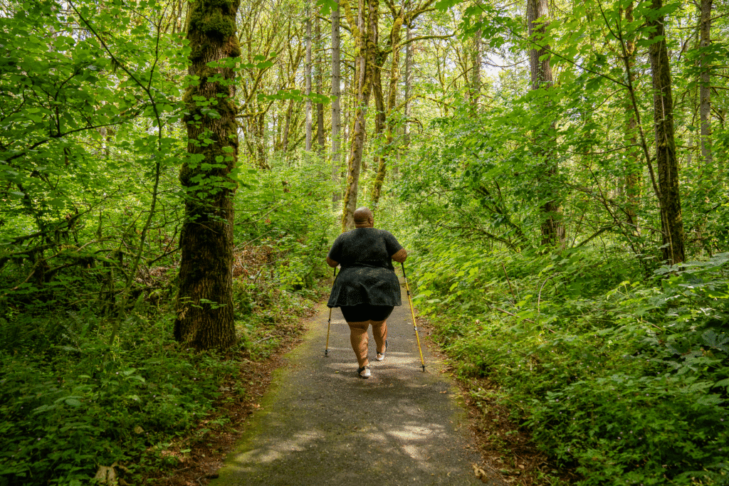 woman working with crutches down a woodland path, through a forest